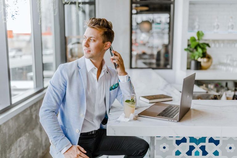 Photo of a young professionnal speaking on the phone while watching throughout the window.